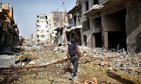 A fighter from an Islamist Syrian rebel group walks among damaged houses in Aleppo