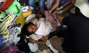Filipino paramedics assist a typhoon survivor giving birth to her baby at a temporary shelter inside a church in Tacloban City.