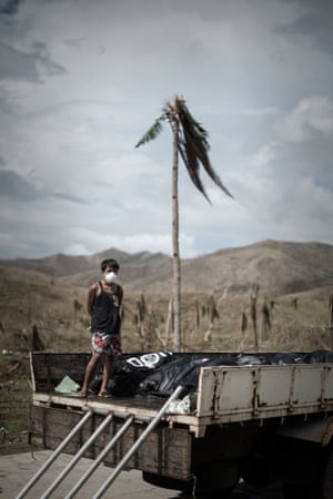 A young volunteer stands on a truck loaded with corpses of victims of typhoon Haiyan before a mass burial in the outskirts of Tacloban.