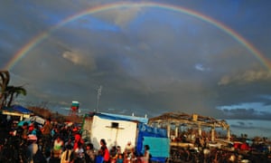A rainbow appears above Typhoon Haiyan survivors desperate to catch a flight from Tacloban airport in the Philippines.