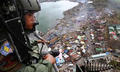 A Philippine Air Force crewman looks out over the typhoon Haiyan-ravaged city of Tacloban