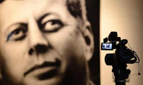A TV camera sits on a tripod filming a picture of John F. Kennedy inside the Sixth Floor Museum in Dallas, Texas