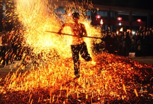 A man walks on burning charcoal as he participates in the traditional ritual called Lianhuo, or fire walking, in Pan'an county, China.