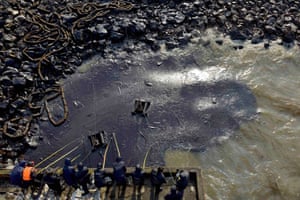 Workers clean up leaked oil after an oil pipeline explosion last week in Qingdao, China.