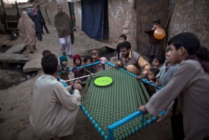 Afghan refugee children watch workers preparing a bed for a customer in an alley of a poor neighbourhood on the outskirts of Islamabad, Pakistan.