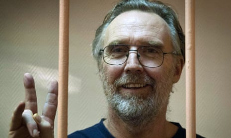 Greenpeace International activist Colin Russell from Australia flashing the V-sign for "victory" while standing in a defendant cage in a court in Russia's second city of Saint Petersburg