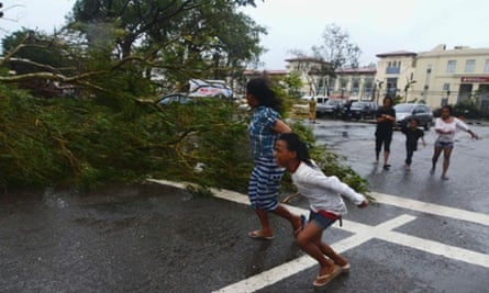 Residents rush to safety past a fallen tree during strong winds brought by Typhoon Haiyan that hit Cebu city, Philippines.