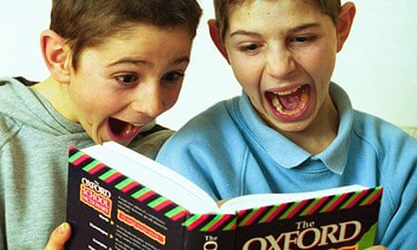 Schoolboys laughing while looking at a dictionary