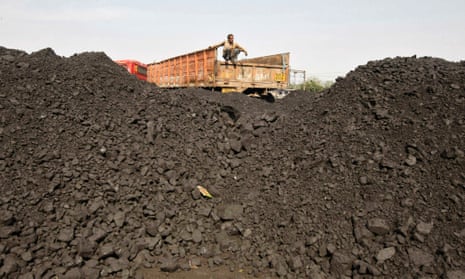 A worker sits on a truck as he waits for the loading of coal at a railway coal yard on the outskirts of the western Indian city of Ahmedabad.