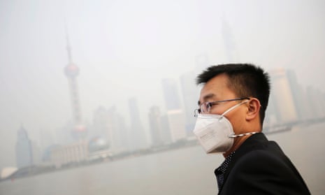 A tourist wearing a protective mask looks at buildings at the Bund under heavy haze in Shanghai