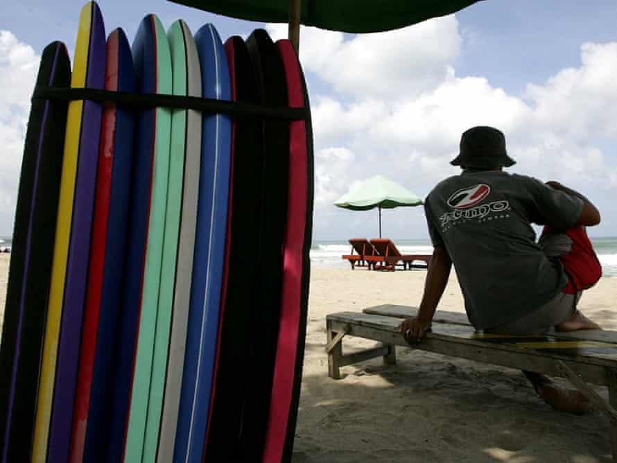 A surf board lender waits for customers at Kuta beach.