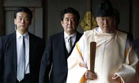 Shinzo Abe, centre, follows a Shinto priest as he visits the Yasukuni shrine for war dead.