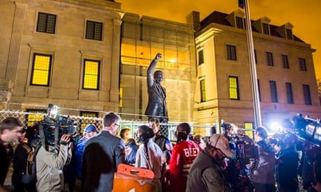 People gathering around a statue of Nelson Mandela at the South African embassy in Washington DC