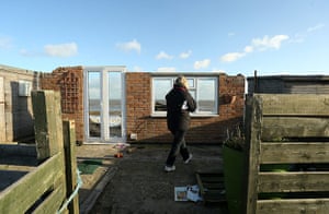 UK weather update: A woman inspects a partially collapsed property in Hemsby