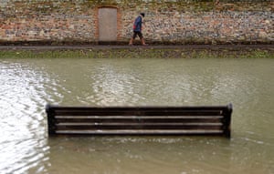 UK weather update: A woman walks along a flooded embankment in Sandwich, Kent