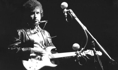 Bob Dylan playing an electric guitar on stage for the first time at Newport Folk Festival in 1965