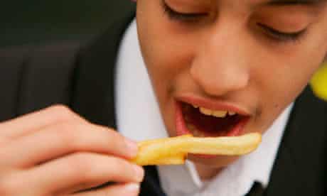 A student eats chips bought from a fast food shop near his school