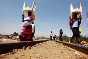 Women carry chairs on their heads as they walk along the Kenya-Uganda railway line near Kibera slum, home to over 1 million people in Kenya's capital Nairobi. Kenya's landlocked neighbours are stocking up on fuel and food to prevent the kind of disruption they suffered after being cut off from the port of Mombasa by angry rioters following a disputed election five years ago.