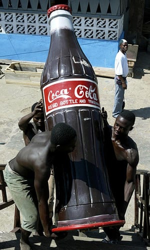Coffins in Ghana: Carpenters lift a coffin shaped like a Coca Cola bottle in Teshie