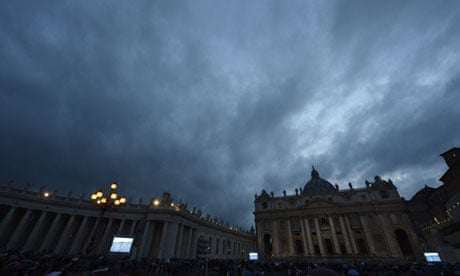 People gather in St Peter's Square watching giant screens showing the chimney on the roof
