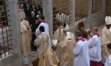 Pope Francis, cross in hand, leaves the Sistine Chapel.