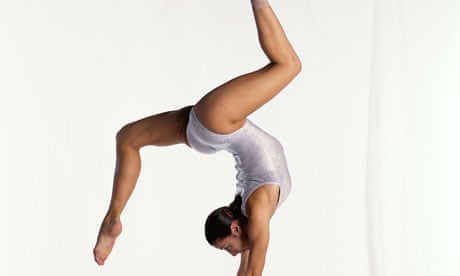 Young female gymnast on balance beam performing, side view
