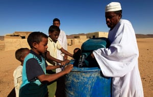 Water in Sudan: a man pours drinking water for children at Hajar Al-assal