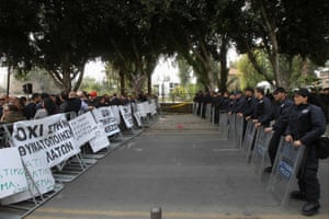 Police officers stand guard in front of protesters during an anti-bailout rally by employees of Cyprus Popular Bank outside the parliament in Nicosia March 22, 2013.