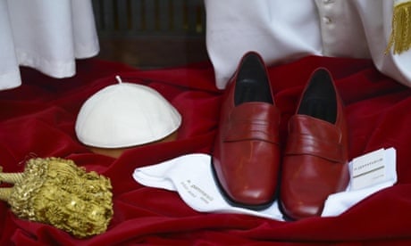 Wanted: one very religious man, uniform supplied. A a white mitre, a band with gold tassels, a cord and a pair of red leather shoes for the future Pope in the window of the Italian taylors shop Gammarelli, behind the Pantheon, Rome, Italy.