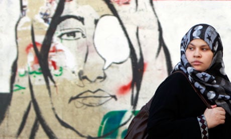 A woman walks past a mural depicting a woman with eye patches near Tahrir Square in Cairo