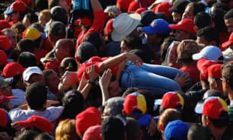 Chavez funeral: A supporter of Venezuela's late president Hugo Chavez is lifted out of the crowd after fainting while waiting for a chance to view his body at the military academy in Caracas on 8 March 2013.