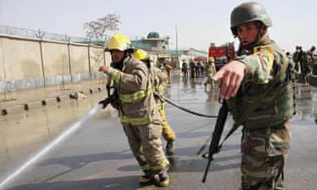 An Afghan soldier directs a firefighter to hose down the scene of a suicide bomb attack in Kabul