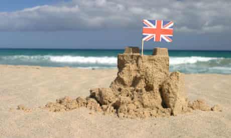 A ruined sand castle with a Union Jack flag pinned on top