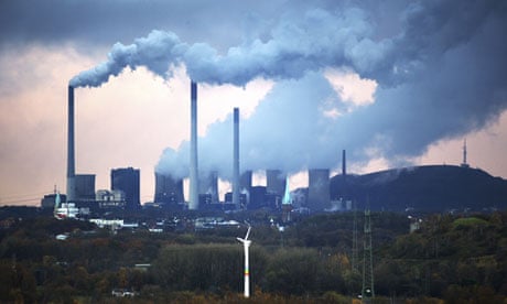 A coal-fired power station in Gelsenkirchen, Germany dwarfs a wind turbine in the foreground.
