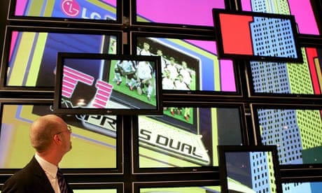 a man watches a wall of video screens