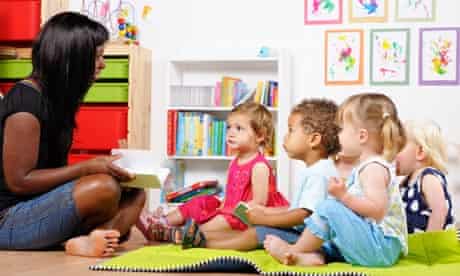 Happy, bright picture of childminder sitting crosslegged reading to four attentive children