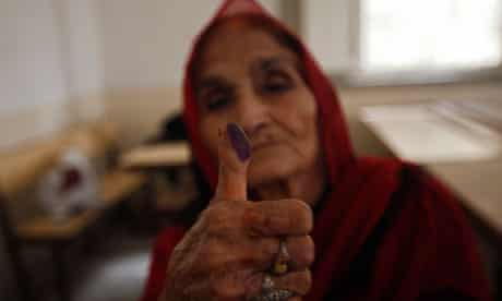 A voter displays her inked thumb after marking her ballot paper at a polling station in Karachi.