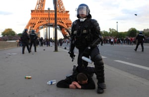 And a fan is detained by a riot police in front of the Eiffel Tower after the clashes between PSG fans and police.