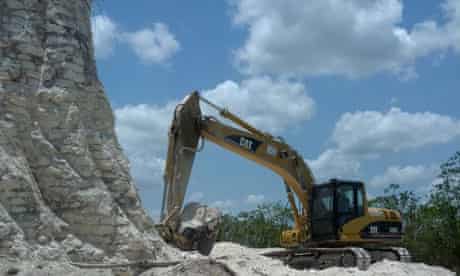 A digger claws away at the sloping sides of the Mayan pyramid in Belize