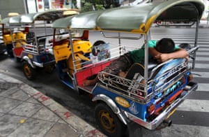 A Tuk-Tuk driver takes a nap as he waits for customers in Bangkok, Thailand.