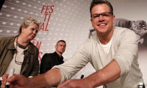 Matt Damon signs autographs as he arrives at a news conference for the Behind the Candelabra