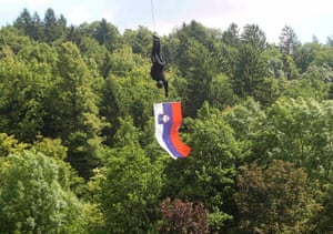 A member of the Special Police Unit holds a Slovenian flag as he descends from a helicopter during an event to celebrate the 40th anniversary of the establishment of their unit, in Tacen.