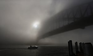 A boat navigates past the Sydney Harbour Bridge, which is covered in thick fog again this morning. Flights and ferry services were suspended and delayed after a blanket of fog covered the city for the second time in as many days.