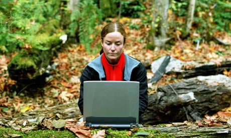 A woman using a laptop computer in the forest