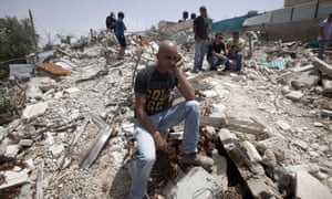 A man sits on the rubble that was once his home.