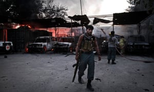 An Afghan policeman is seen at the burning International Red Cross building. A senior Afghan official said security forces rescued seven foreigners working for the International Red Cross on Wednesday after a two-hour-long gun battle with an insurgent at a guest house in the eastern city of Jalalabad.