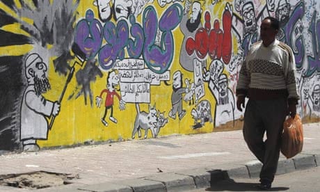 A man walks past graffiti depicting the Muslim Brotherhood along Mohamed Mahmoud Street in Cairo