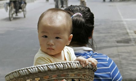 A baby is carried in a basket on his mother's back, Beijing.