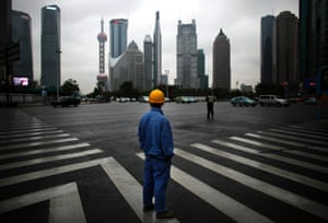 A construction worker looks at Pudong financial district as he waits to cross an avenue in Shanghai. The International Monetary Fund cut its growth forecast for China this year from 8% to 7.75%, citing a weak world economy and exports – adding to concerns that the world's second-largest economy is losing momentum. 