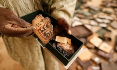 A museum guard displays a burnt ancient manuscript at the Ahmed Baba Institute in Timbuktu